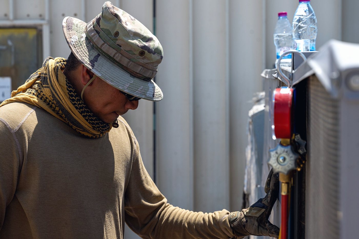 A technician reading a red gauge dial mounted on equipment lines