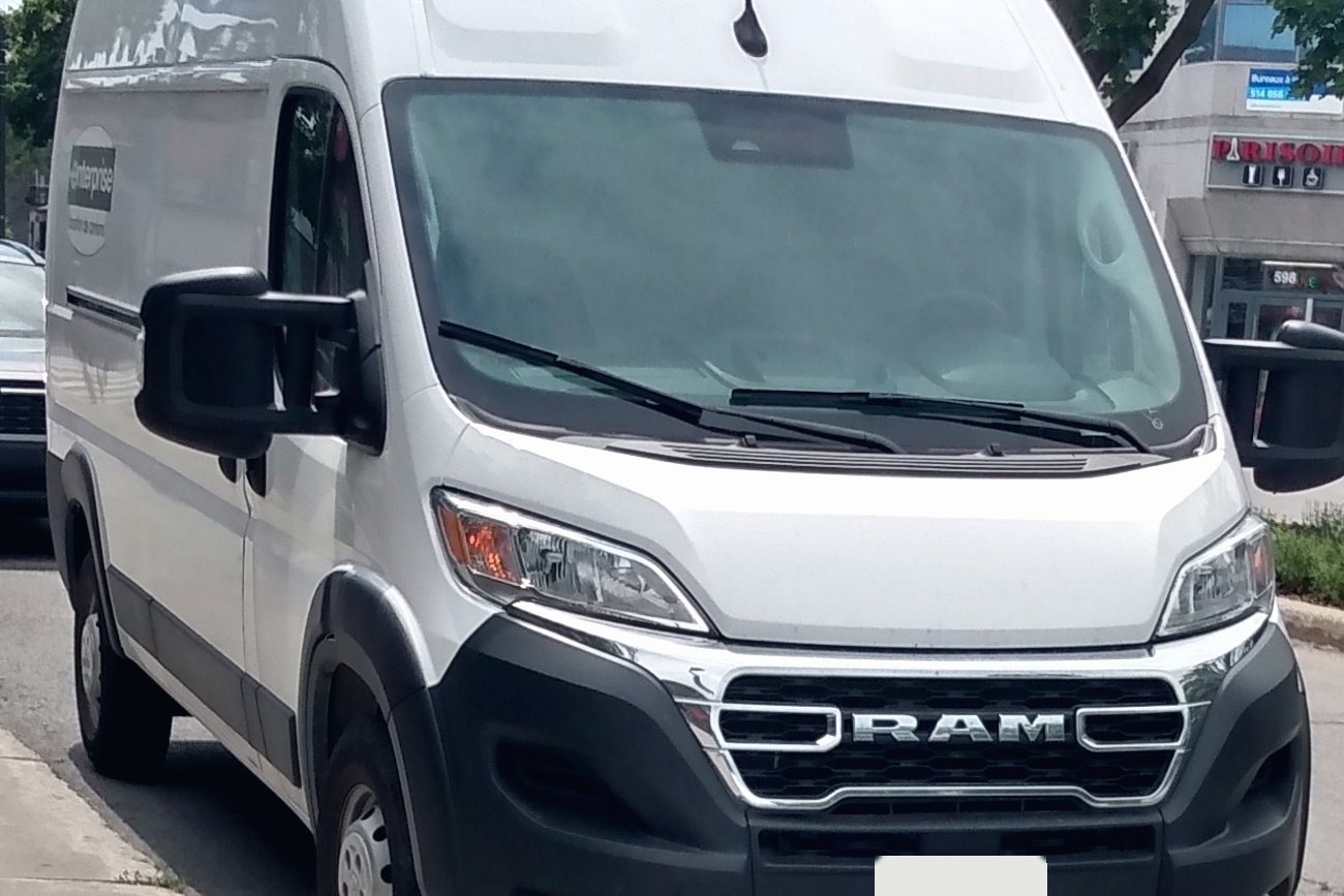 A plain white Ram ProMaster high-roof van parked at a curb
